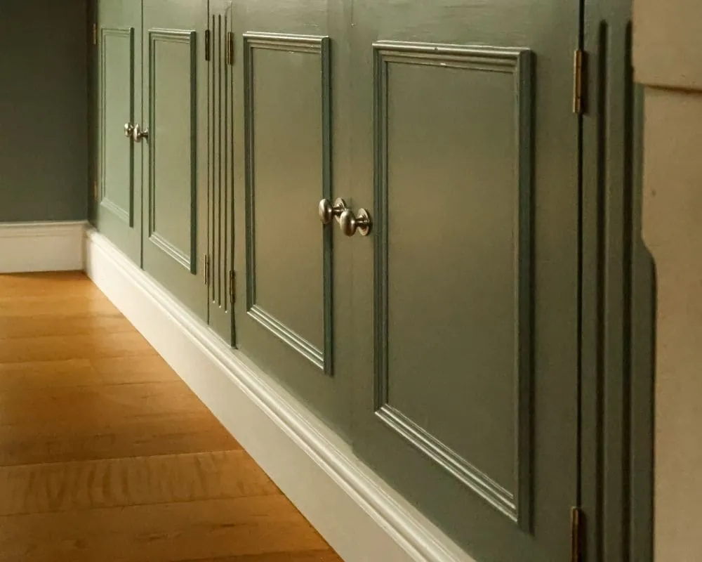 After: the same cabinet doors finished in a deep sage green with the brass handles refitted