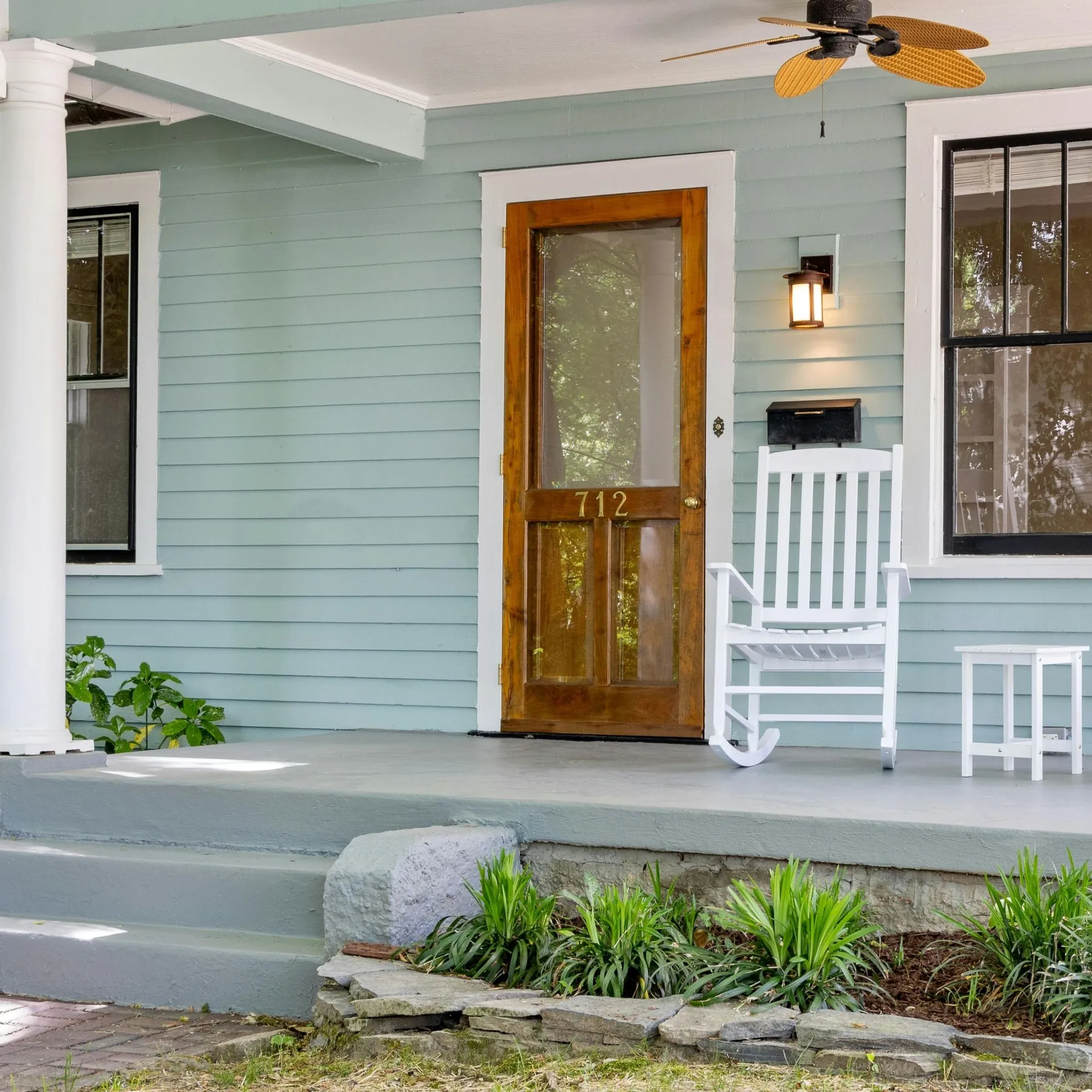 Craftsman home with pale blue siding, a natural wood front door, and a white porch rail