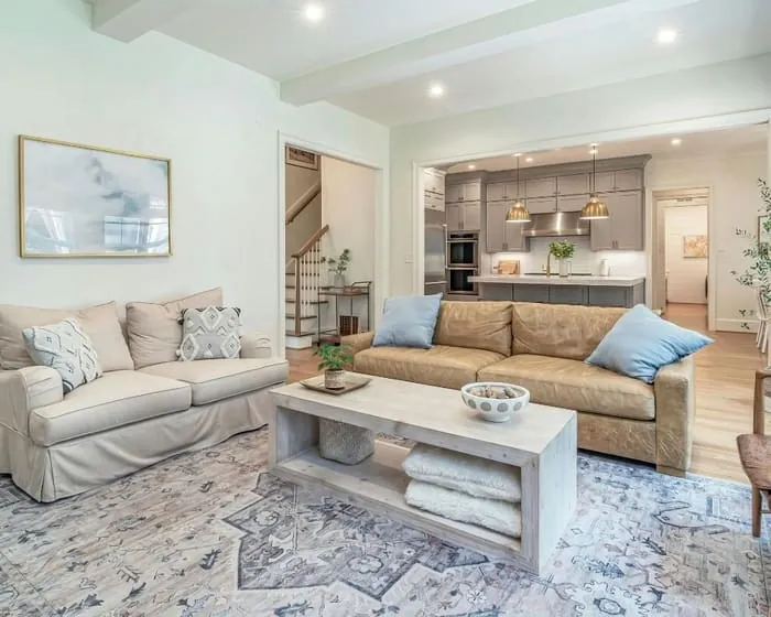 Living room painted in a soft sage green, open through to a kitchen beyond