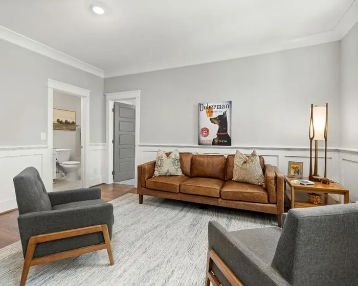 Sitting room with grey walls above white panelled wainscoting and painted door casings