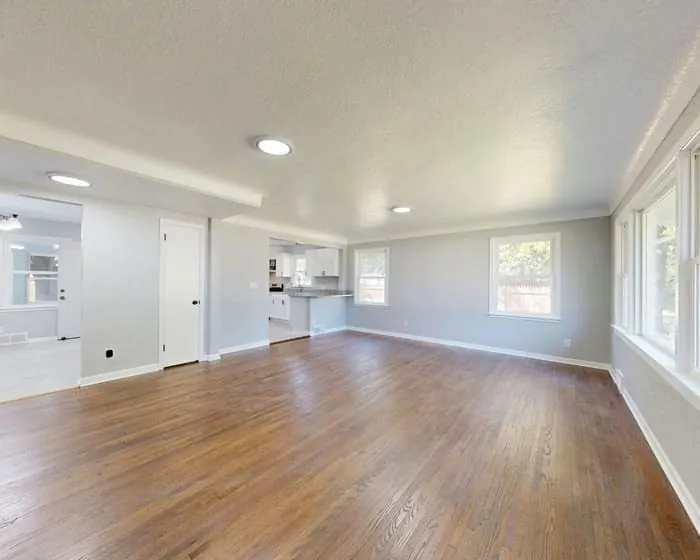 Empty room repainted in a warm greige, with white trim and dark timber flooring