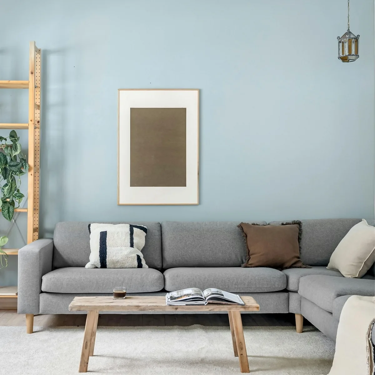 Living room wall painted in a soft blue-grey, with a framed print hung above a grey sofa