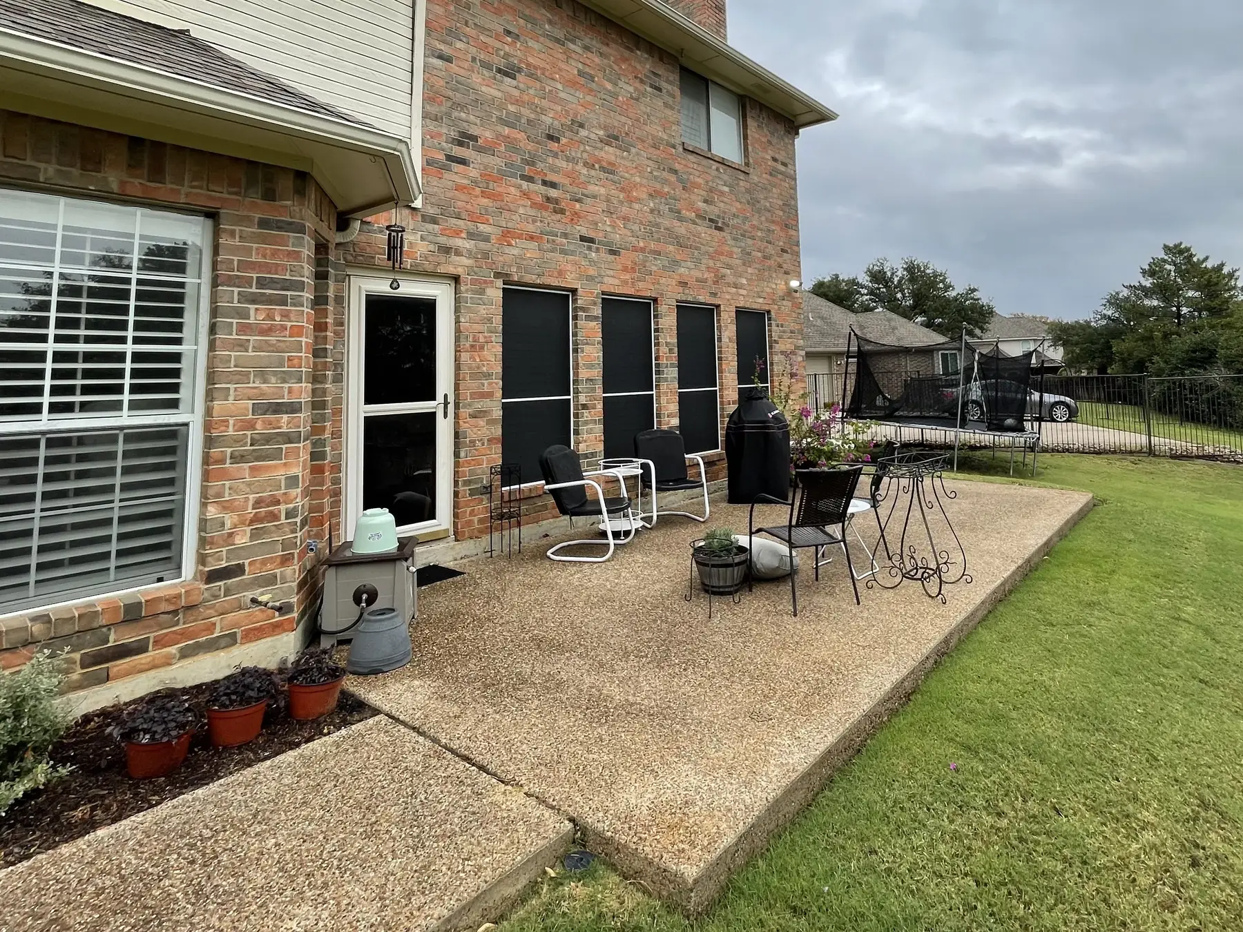 Covered patio and lawn at the rear of a brick home