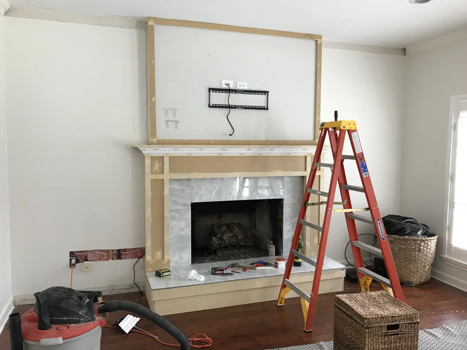 Before: fireplace wall stripped back with a mounting bracket and stepladder in place