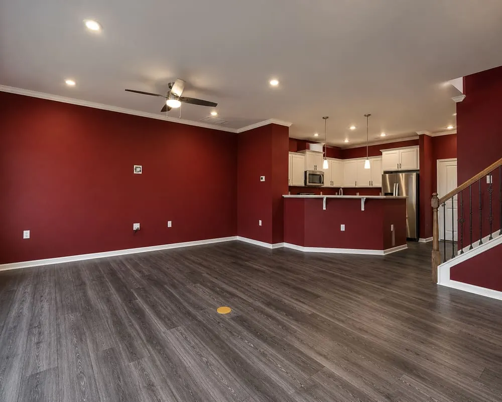 Before: open-plan living room with a dark red accent wall running through to the kitchen
